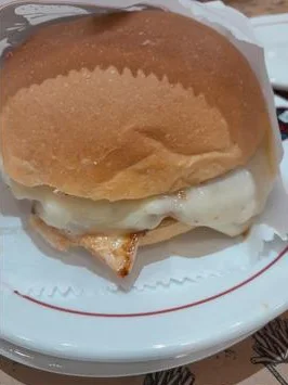 Hambúrguer com queijo derretido no papel, servido em prato branco na Pompéia's Burger